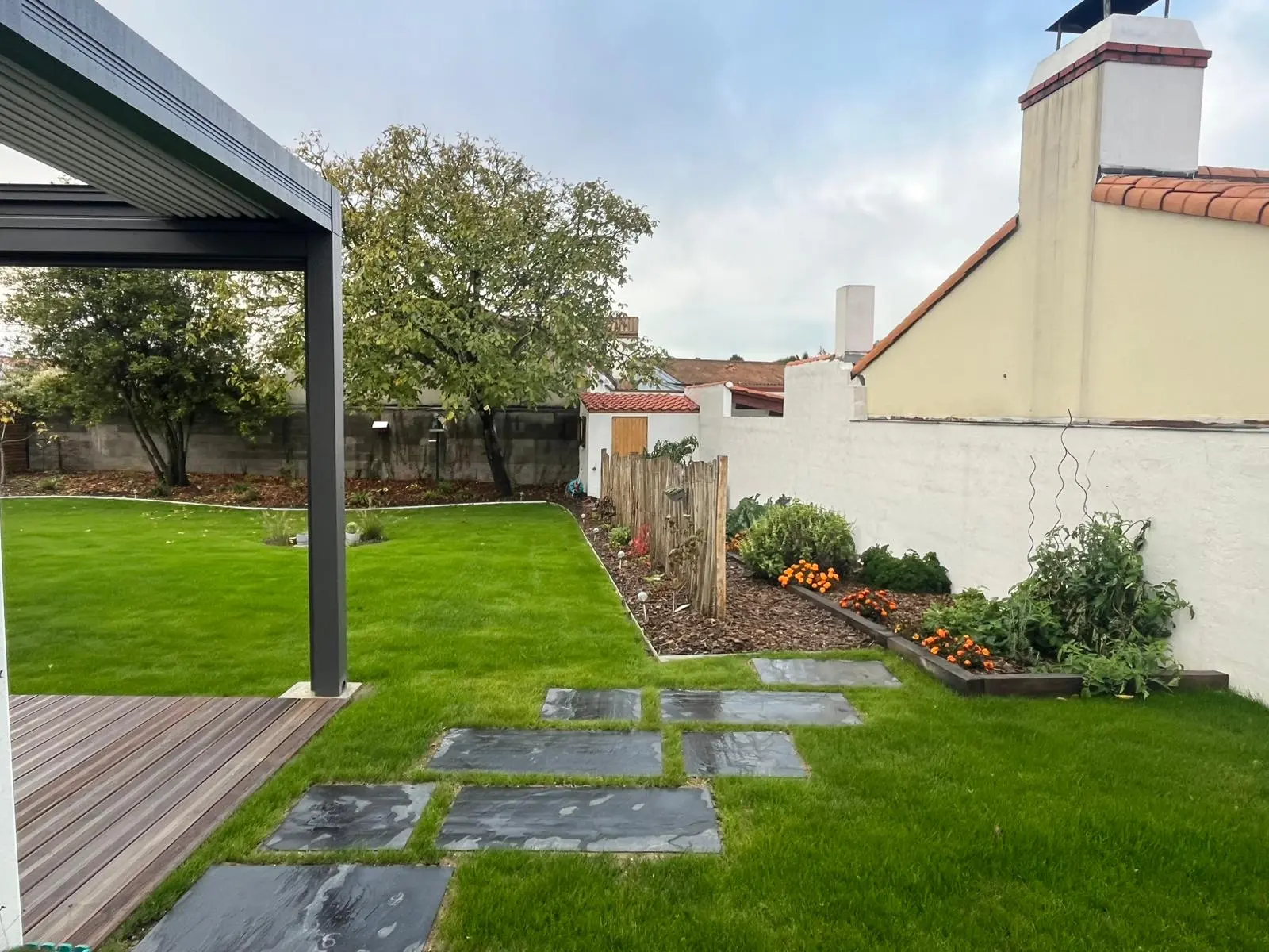 Jardin aménagé avec pergola, pas japonais en ardoise et massifs fleuris